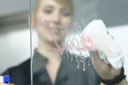 Junge Geschäftsfrau reinigt Glasscheibe mit Lappen